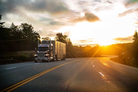 Semi-truck driving down a lonely highway at dusk